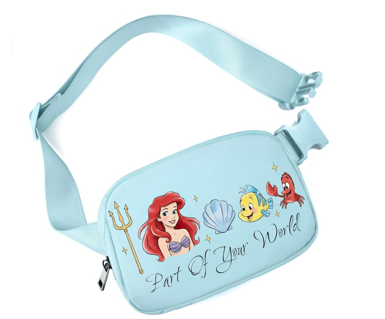 May include: Pale blue fanny pack featuring Ariel, Flounder, and Sebastian from The Little Mermaid. The pack has a matching adjustable strap and a zip closure. Text on the pack reads "Part Of Your World".