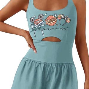 May include: A light blue romper with a scoop neck and a keyhole cutout. The top features a graphic of a cartoon car, the text "Rusteze", and the phrase "I eat losers for breakfast."