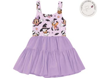 Puede incluir: Vestido activo de malla lavanda con cuello redondo y falda escalonada. El corpiño presenta un estampado de personajes de dibujos animados con disfraces de Halloween. El texto "Preorder • Limited Batch" y "Active Mesh Dress" son visibles.