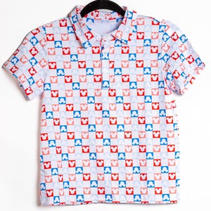 May include: A short-sleeved polo shirt featuring a repeating checkerboard pattern of red, light blue, and white squares. Each square contains a white Mickey Mouse head silhouette. The shirt has a classic collar and a three-button placket front.