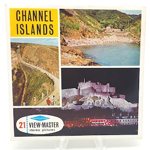 以下が含まれることがあります： 黄色い背景に黒い文字で「CHANNEL ISLANDS」と書かれたビューマスターのリールボックス。箱には、曲がりくねった道、岩だらけの海岸線のあるビーチ、夜の城、夜の街の明かりが灯る街の4つの画像が描かれている。箱には、青と白の文字で「21 VIEW-MASTER stereo pictures」と書かれている。