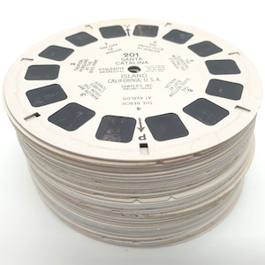 Könnte beinhalten: Ein Stapel weißer View-Master-Rollen mit Schwarzweißbildern von Santa Catalina Island, Kalifornien. Die Rolle ist mit "201 Santa Catalina Island, California, U.S.A. Sawyer's Inc. Portland 1, Oregon" beschriftet.