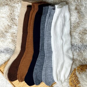 May include: Seven pairs of long knitted socks in various colors, including beige, brown, black, gray, and white. The socks are arranged in a row, with the toes facing the viewer.