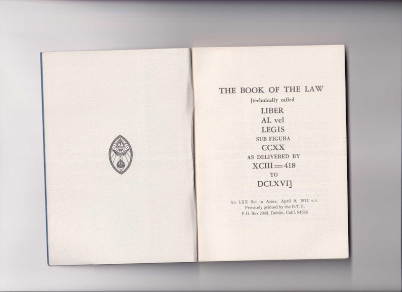 May include: A book titled "The Book of the Law" with the subtitle "[technically called Liber AL vel Legis Sub Figura CCXX As Delivered by XCIII=418 to DCLXVI]" and the text "An LXX in Aries. April 9, 19... Privately printed by the O.T.O. P.O. Box 2041, Dublin, Calif. 94566".