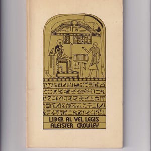 May include: A book cover with a gold background and a black and white illustration of an Egyptian hieroglyphic stele. The text on the cover reads "Liber Al Vel Legis Aleister Crowley".