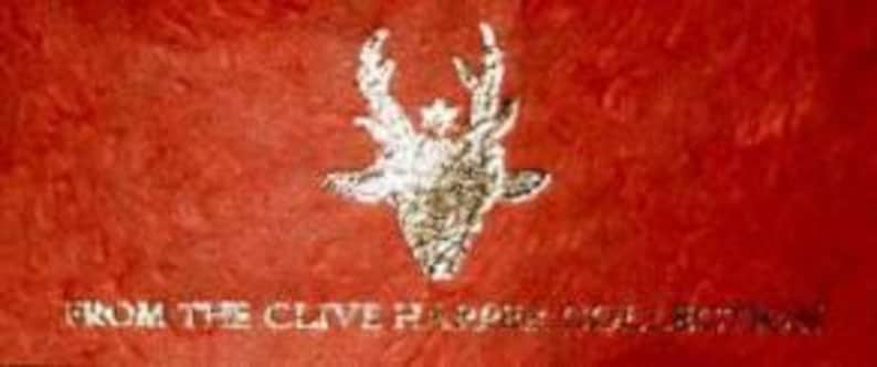 May include: A red background with a silver stag head with antlers and the text "from the Clive Harper Angel Button"