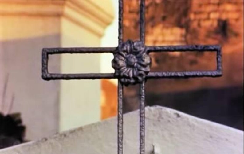 May include: A black metal cross with a decorative flower design in the center.