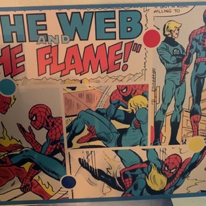 Könnte beinhalten: Ein rechteckiger Comic-Druck mit Spider-Man und der Human Torch mit dem Text THE WEB AND THE FLAME. Das Kunstwerk zeigt mehrere Panels mit den Charakteren in Aktion und verwendet eine Farbpalette aus Rot, Blau und Gelb.