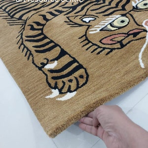 May include: A brown rug with a black and white tiger design. The tiger's face is visible, with black stripes and white accents. The rug has a fringe border.