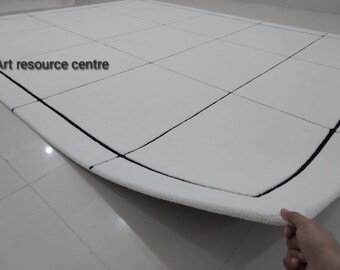 Può includere: Un tappeto bianco con un motivo a griglia nera. Il tappeto è arrotolato e il bordo è visibile. Il testo "Art resource centre" è visibile nell'angolo in alto a sinistra dell'immagine.