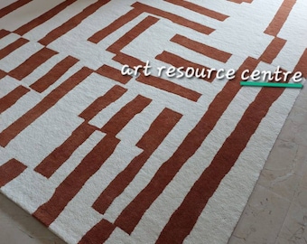May include: A white and brown geometric patterned rug with a modern design. The rug has a white background with brown stripes and geometric shapes.