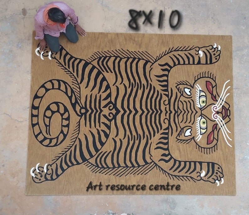May include: A black and white tiger illustration on a brown wooden background. The tiger is lying on its back with its paws in the air. The text "Art resource centre" is printed below the tiger.