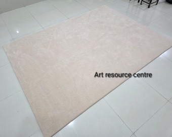 May include: A large, rectangular beige rug with a soft, textured surface. The rug is placed on a tiled floor. The text "Art resource centre" is visible on the rug.