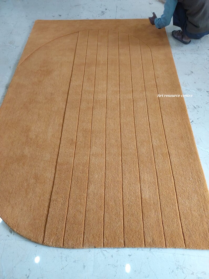 Puede incluir: Una alfombra grande, rectangular, de color marr&oacute;n claro con un borde curvo y l&iacute;neas verticales paralelas. La alfombra est&aacute; hecha de un material suave y es adecuada para una sala de estar o un dormitorio. El texto "Art resource centre" es visible.