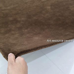 May include: A brown rug with a soft, plush texture. The rug is a solid colour and appears to be made of a dense material. The text "Art resource centre" is visible in the upper right corner.