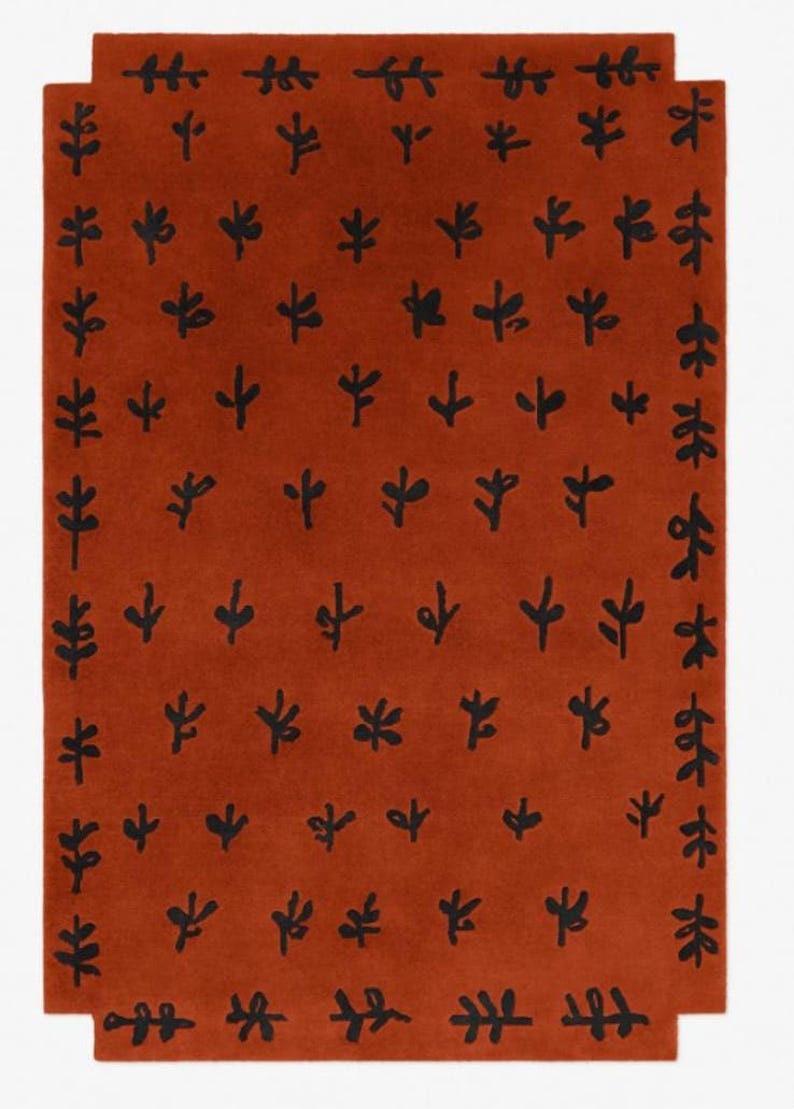 Puede incluir: Una alfombra de color &oacute;xido con un patr&oacute;n repetitivo de hojas estilizadas negras.