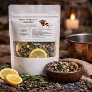 May include: A white pouch labeled "Spring Awakening Simmer Pot" with ingredients and directions. The pouch contains dried lemon slices, herbs, and spices. A wooden bowl holds a similar mixture. A copper pot and lit candle are in the background.