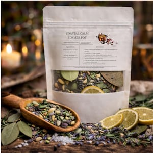 May include: A white pouch labeled "Coastal Calm Simmer Pot" with a clear window showing dried herbs, spices, and lemon slices. A wooden scoop filled with herbs sits in front. The ingredients include dried lime slices, bay leaf, lavender, and sea salt.