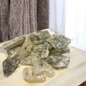 Pu&ograve; includere: Un mucchio di caramelle dure traslucide verdi e bianche con un aspetto maculato. Le caramelle sono rotte in forme e dimensioni irregolari.