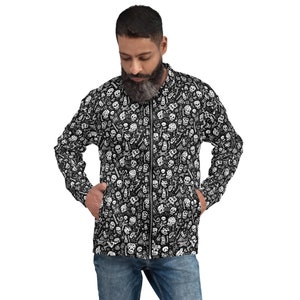 Könnte beinhalten: Eine schwarze Reißverschlussjacke mit einem weißen Totenkopf- und Knochenmuster. Die Jacke hat einen Stehkragen und zwei Fronttaschen.