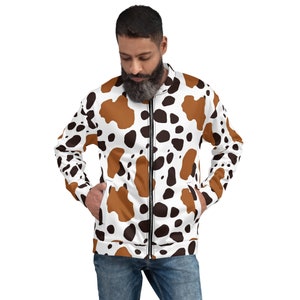 May include: A white bomber jacket with a brown and black cow print pattern. The jacket has a zipper closure and two pockets.
