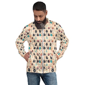 Może przedstawiać: Beżowa kurtka bomberowa z kolorowym nadrukiem różnych gitar elektrycznych. Kurtka ma zamek błyskawiczny i dwie kieszenie.