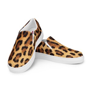 May include: A pair of white canvas slip-on shoes with a leopard print design.