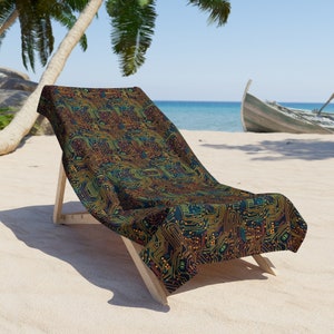 Op de afbeelding: Een strandstoel met een kleurrijk printpatroon van een printplaat op de stof. De stoel is gemaakt van hout en heeft een donkerbruine afwerking. De stoel staat op een zandstrand met een blauwe zee op de achtergrond.