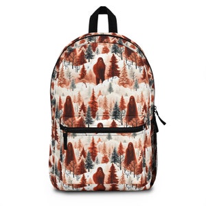 May include: A brown backpack with a white background featuring a repeating pattern of a red-haired sasquatch standing in a snowy forest.