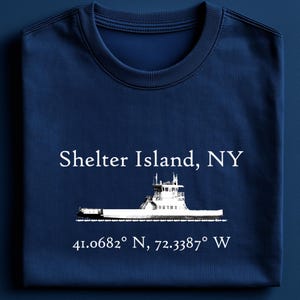 May include: A navy blue t-shirt with a white graphic of a ferry boat and the text "Shelter Island, NY 41.0682° N, 72.3387° W".