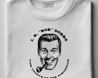 May include: White t-shirt with a black and white illustration of a man with a pipe. The text reads "J.R. "BOB" DOBBS THE CHURCH OF THE SUBGENIUS".