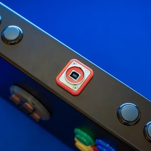 Pode incluir: Um painel de controle preto com vários botões redondos e um quadrado vermelho com uma porta USB.