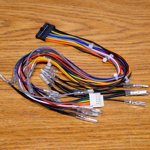 May include: A bundle of colorful electrical wires with various connectors. The wires are in multiple colors, including red, yellow, blue, and black. The wires are on a wooden surface.