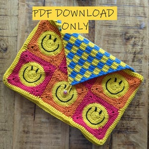 May include: A crocheted blanket with a checkered pattern in blue and yellow. The blanket is made up of squares with smiley faces in yellow and black on a red, orange, and yellow background. The text "PDF DOWNLOAD ONLY" is written in black on a yellow background.