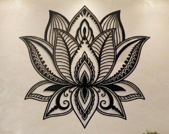 May include: A black metal wall art piece shaped like a lotus flower with intricate cut-out patterns. The design features symmetrical petals with detailed line work, mounted centrally on a light-colored wall above a massage table in a room.