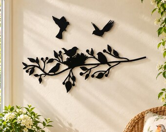 May include: A black metal wall art piece featuring a horizontal tree branch with leaves, berries, and several birds. The design includes birds perched on the branch, one sitting in a nest, and two birds in flight above the branch.