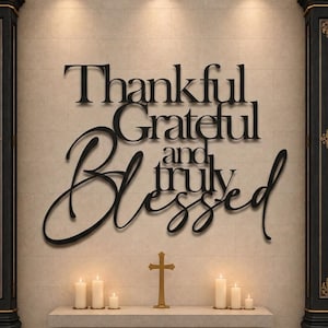 Könnte beinhalten: Ein schwarzes Wand-Schild mit den Wörtern Thankful, Grateful, and truly Blessed in einer Kombination aus Serif- und Schreibschrift. Das Schild ist an einer hellen Wand über einem Steinaltar mit einem kleinen Kreuz und brennenden Kerzen angebracht.