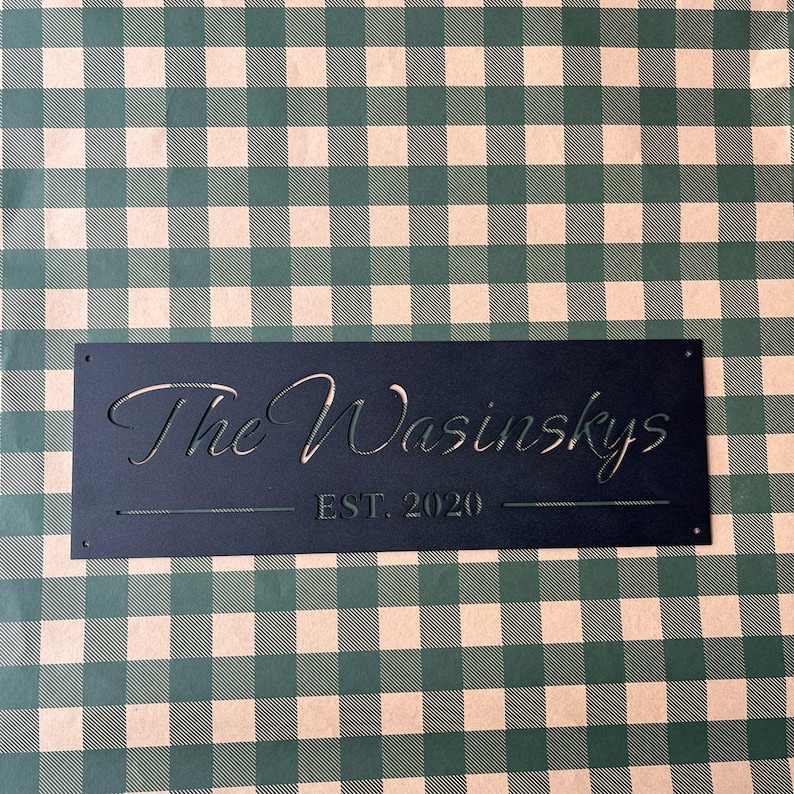 a black rectangular sign with the text "The Wainskys EST. 2020" on it, placed on a green and white checkered background.