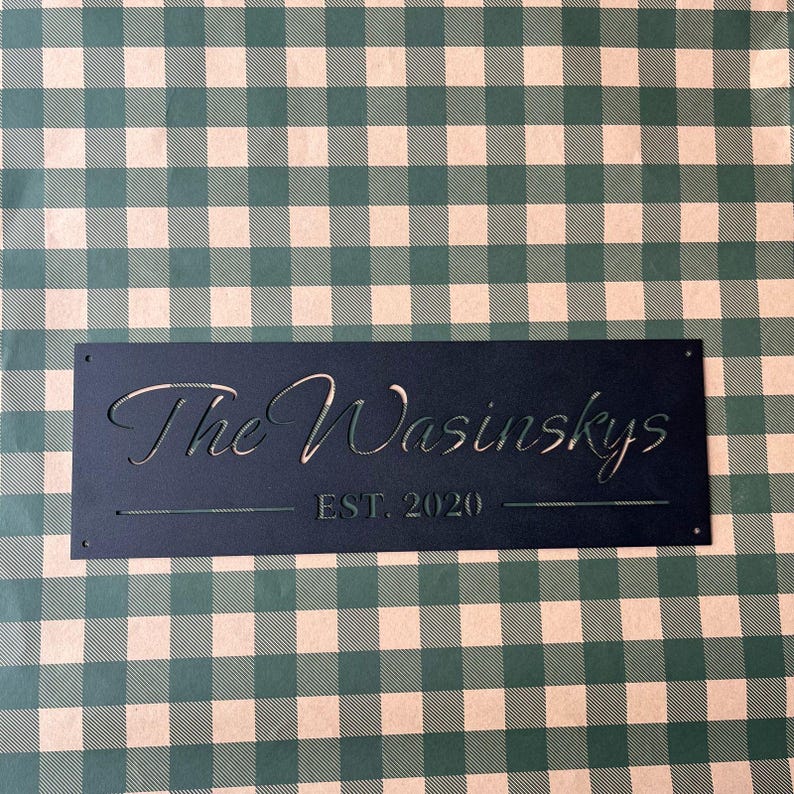a black rectangular sign with the text "The Wainskys EST. 2020" on it, placed on a green and white checkered background.