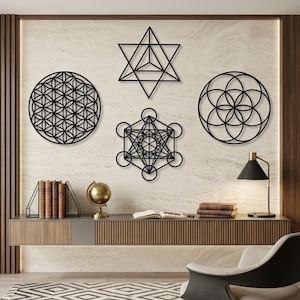 May include: Black metal wall art featuring geometric shapes, including a flower of life, Metatron's Cube, and a star tetrahedron. The art is displayed on a textured, light-colored wall above a modern console table with books and a globe.
