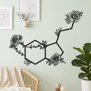 May include: A black metal wall art piece depicting a chemical molecular structure. The design features two connected hexagonal rings adorned with detailed floral and leaf motifs, with additional flowers extending from the structure.