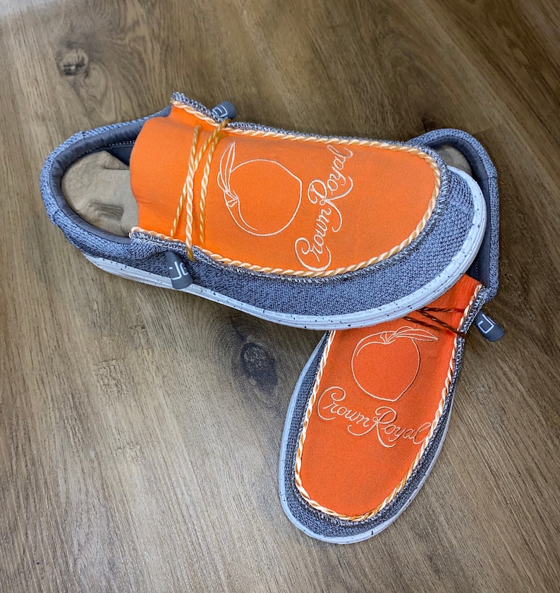 May include: A pair of orange and gray slip-on shoes with a peach design and the text "Crown Royal" embroidered on the top.
