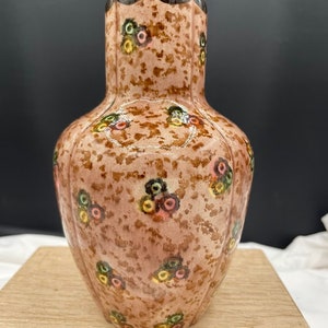 Może przedstawiać: Brązowy ceramiczny wazon z pstrokatą glazurą i kwiatowym wzorem w odcieniach różowego, zielonego i żółtego.