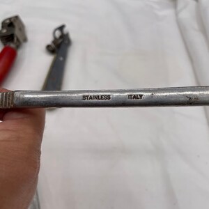 May include: A close-up of a silver metal tool with the words "Stainless Italy" engraved on the handle.