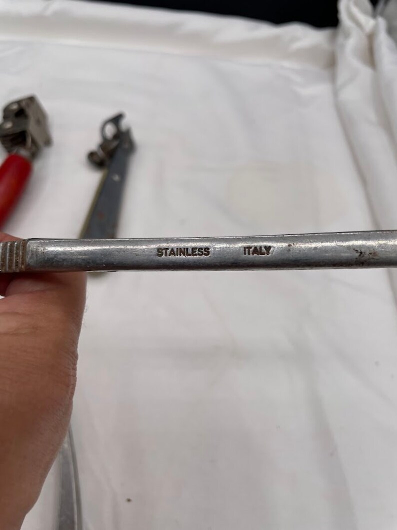 May include: A close-up of a silver metal tool with the words "Stainless Italy" engraved on the handle.