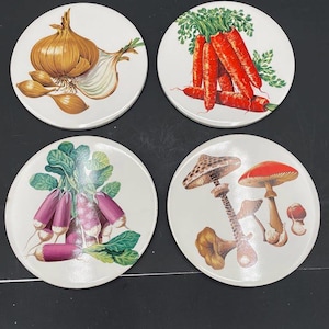 Puede incluir: Conjunto de cuatro posavasos de cerámica blanca con ilustraciones coloridas de verduras y champiñones. Los posavasos presentan una cebolla, zanahorias, rábanos y champiñones.