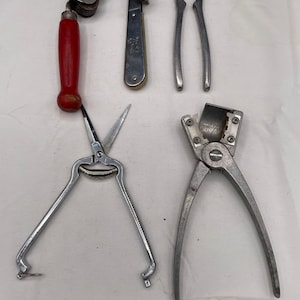 May include: Five different kitchen tools, including a can opener, nutcracker, and a pair of scissors. The tools are all made of metal and have a silver finish.
