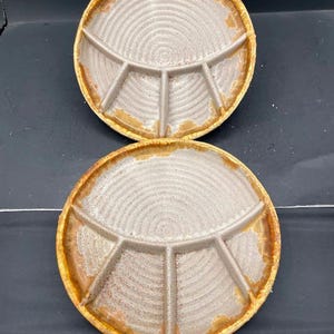 May include: Two round ceramic divided plates featuring a light beige center with a concentric circular texture and a wide, textured golden-brown rim. Each plate is partitioned into four distinct sections by raised dividers radiating from the center.