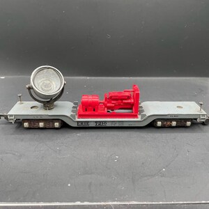 Könnte beinhalten: Ein grauer Modellzugwagen mit einem roten Motor und einem weißen Scheinwerfer oben. Der Wagen ist mit "ERIE 7210" beschriftet.