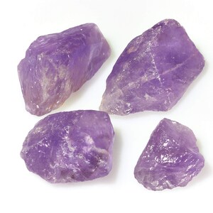 Könnte beinhalten: Vier rohe Amethyst-Kristalle in verschiedenen Größen und Formen. Die Kristalle sind tiefviolett und haben eine natürliche, raue Textur.